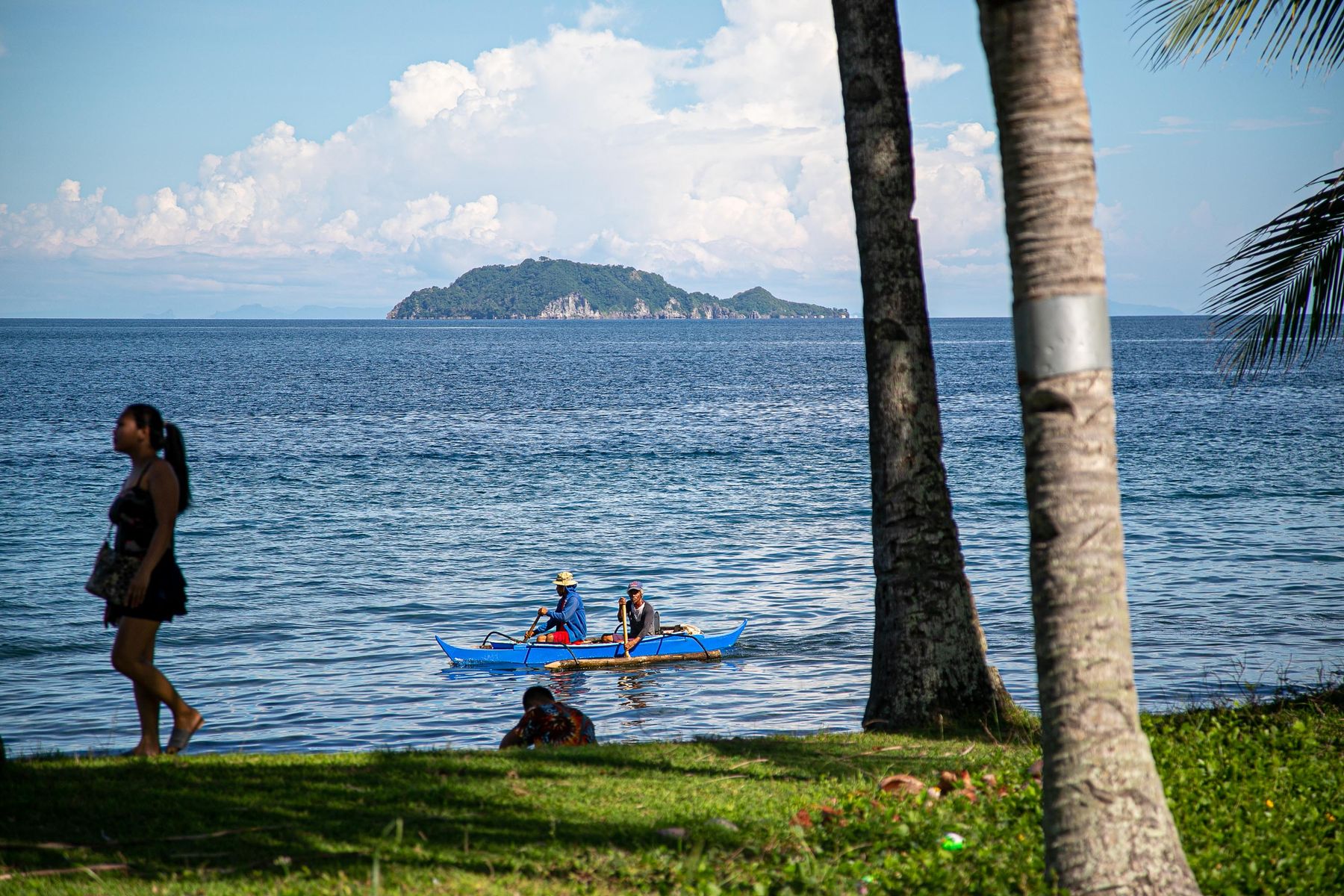 People beside a traditional boat on the coast of Dauin in the Philippines